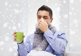 Image showing ill man with flu drinking tea and blowing nose