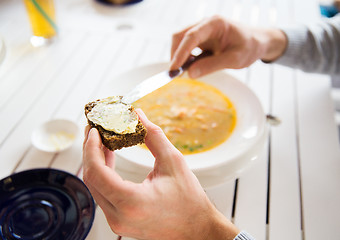 Image showing close up of hands applying butter to bread