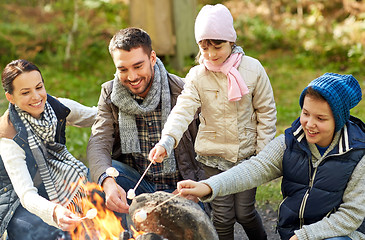 Image showing happy family roasting marshmallow over campfire