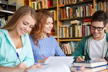 Image showing happy students writing to notebooks in library