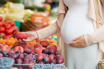 Image showing pregnant woman choosing fruits at street market