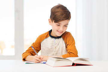 Image showing smiling student boy writing to notebook at home