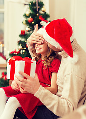 Image showing smiling father surprises daughter with gift box