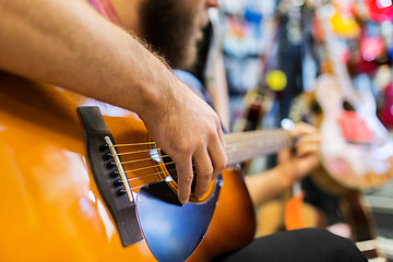 Image showing close up of man playing guitar at music store