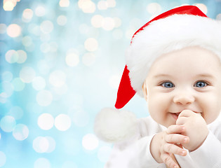 Image showing happy baby in santa hat over blue holidays lights