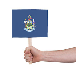 Image showing Hand holding small card - Flag of Maine