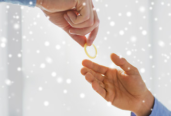 Image showing close up of male gay couple hands giving condom