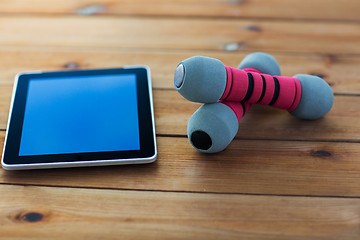 Image showing close up of dumbbells and tablet pc on wood