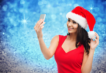 Image showing woman in santa hat taking selfie by smartphone