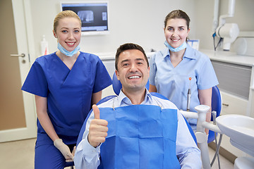 Image showing happy female dentists with man patient at clinic