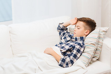 Image showing ill boy lying in bed and suffering from headache