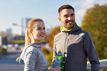 Image showing smiling couple with bottles of water outdoors