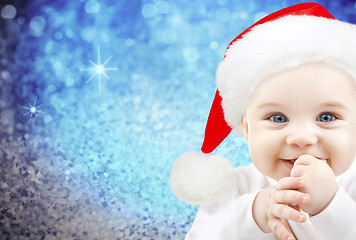 Image showing happy baby in santa hat over blue holidays lights