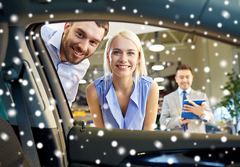 Image showing happy couple with car dealer in auto show or salon