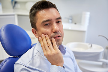 Image showing man having toothache and sitting on dental chair