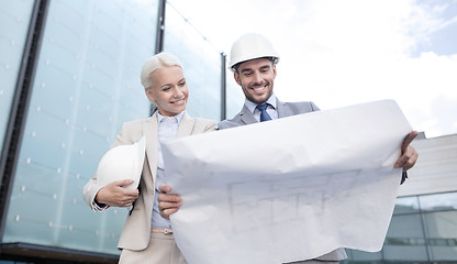 Image showing smiling businessmen with blueprint and helmets