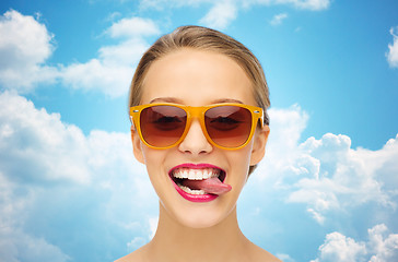 Image showing happy young woman in sunglasses showing tongue