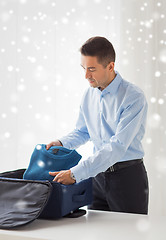 Image showing businessman packing clothes into travel bag