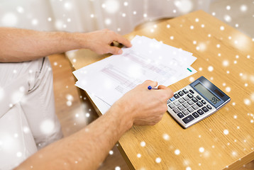 Image showing close up of man with papers and calculator at home