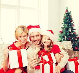 Image showing happy family in santa helper hats with gift boxes