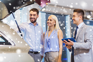 Image showing happy couple with car dealer in auto show or salon