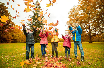 Image showing happy children playing with autumn leaves in park