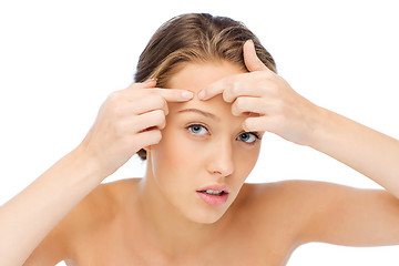 Image showing young woman squeezing pimple on her face