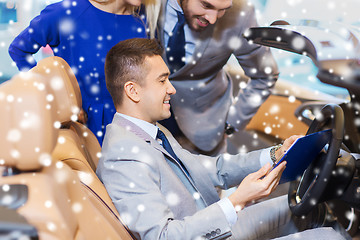 Image showing happy couple with car dealer in auto show or salon