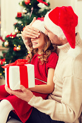 Image showing smiling father surprises daughter with gift box