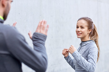 Image showing happy woman with coach working out strike outdoors