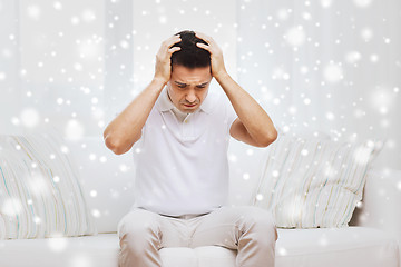 Image showing unhappy man suffering from head ache at home