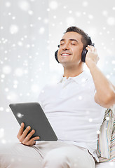 Image showing smiling man with tablet pc and headphones at home