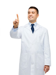 Image showing smiling male doctor in white coat pointing finger