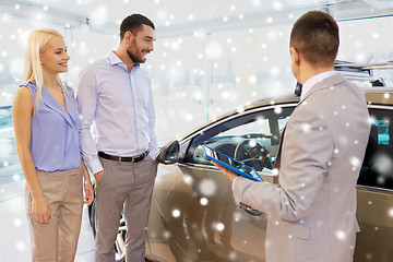 Image showing happy couple with car dealer in auto show or salon