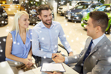 Image showing happy couple with car dealer in auto show or salon