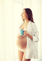 Image showing happy pregnant woman with cup drinking tea at home