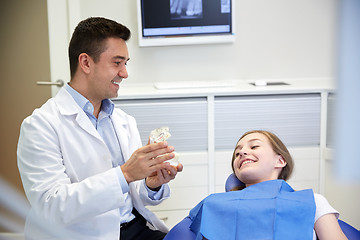 Image showing happy dentist showing jaw layout to patient girl