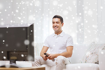 Image showing smiling man with remote control watching tv