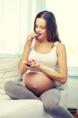 Image showing happy pregnant woman eating fruits at home