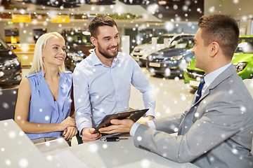 Image showing happy couple with car dealer in auto show or salon