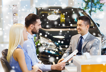 Image showing happy couple with car dealer in auto show or salon