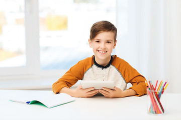 Image showing smiling boy with tablet pc and notebook at home