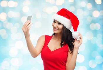 Image showing woman in santa hat taking selfie by smartphone