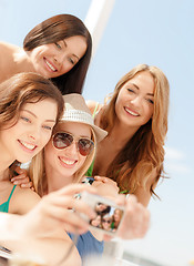 Image showing smiling girls taking photo in cafe on the beach