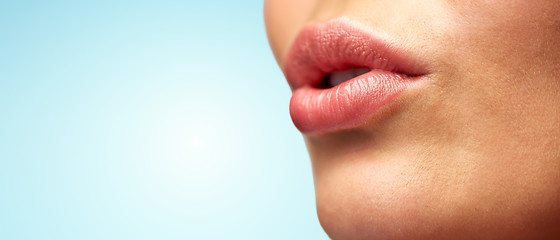 Image showing close up of young woman lips over blue