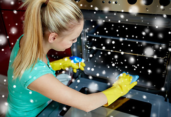 Image showing happy woman cleaning cooker at home kitchen