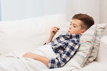 Image showing ill boy with flu and thermometer at home