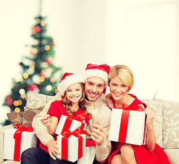 Image showing smiling family holding gift boxes and sparkles