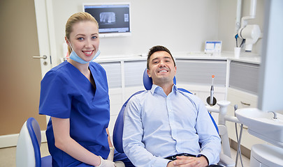 Image showing happy female dentist with man patient at clinic