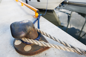 Image showing rusted iron mooring bollard with rope on pier